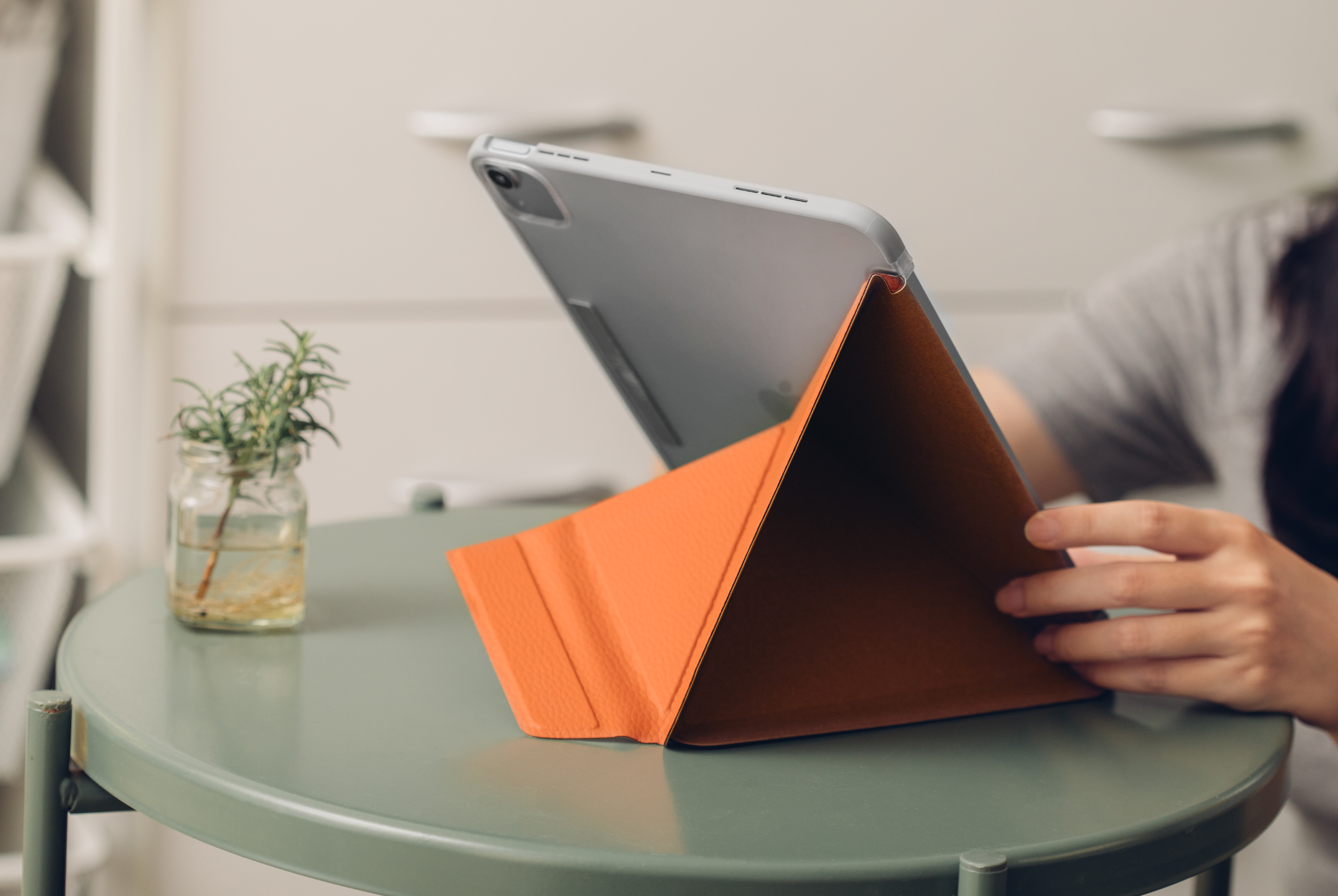 A woman using an iPad with Moshi VersaCover case, standing in portrait orientation